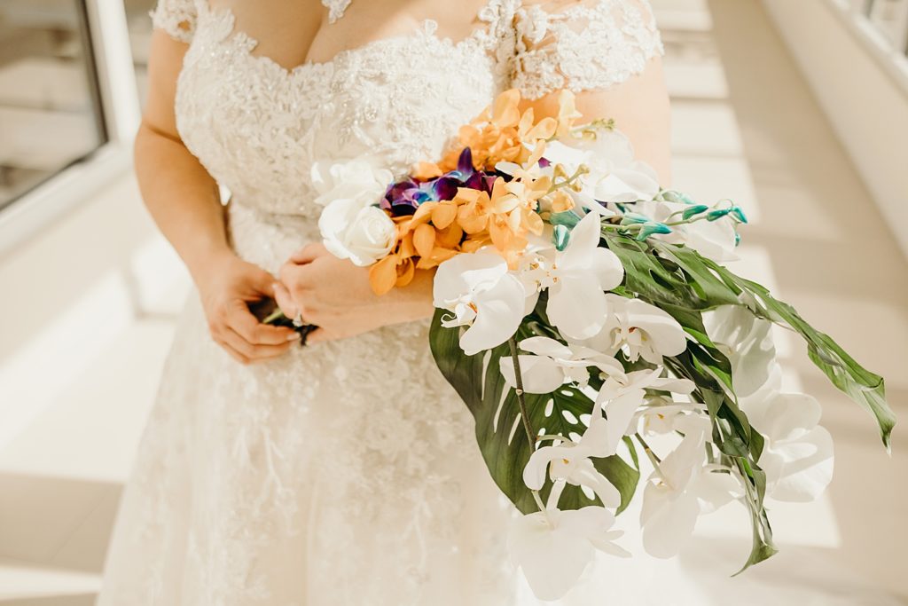 Closeup of Bride holding tropical orange and green leaf bouquet