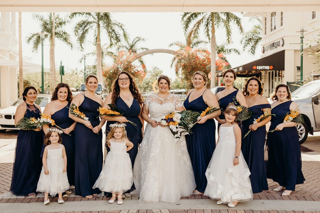 Bride Bridesmaids and flower girls posing with bouquets in front of palm trees