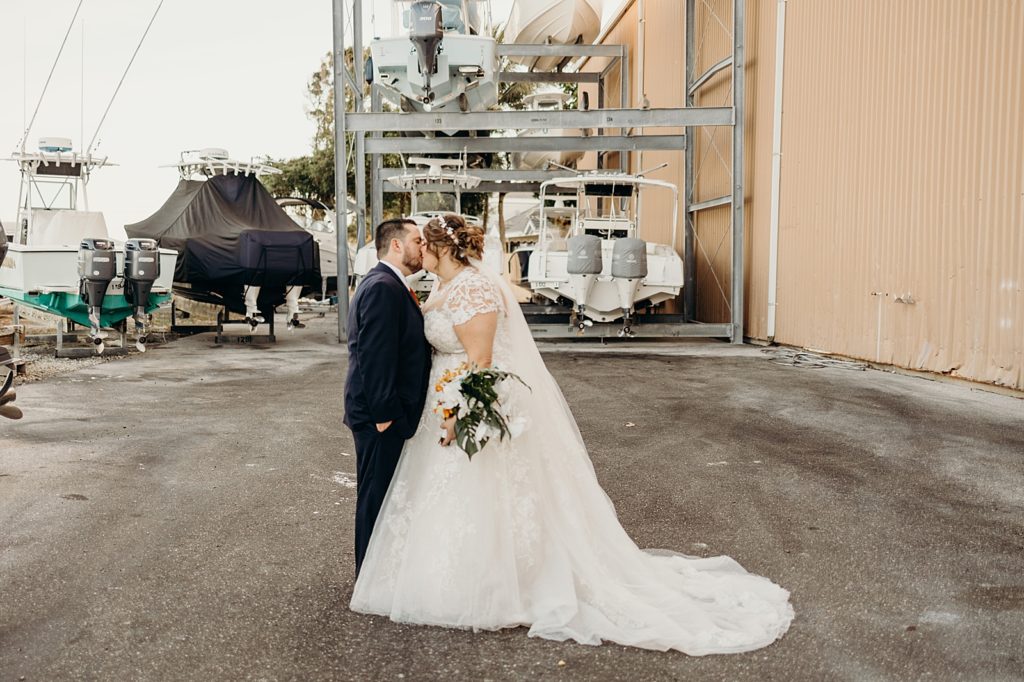 Bride and Groom kissing by boat maintenance area