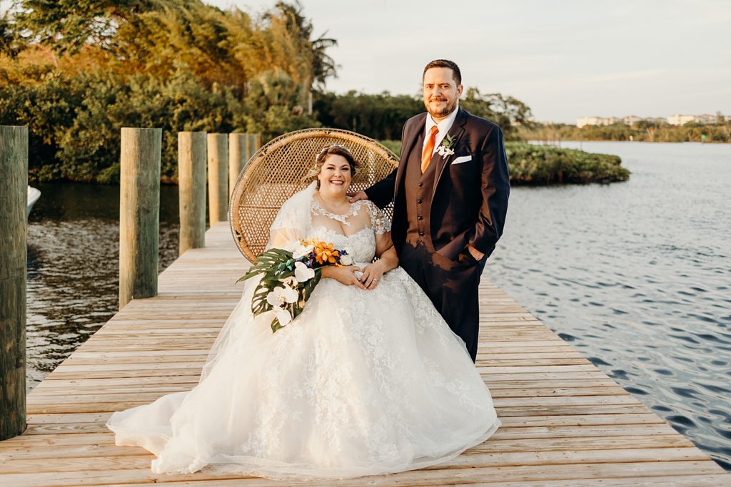 Bride sitting on chair on the dock with Groom next to her