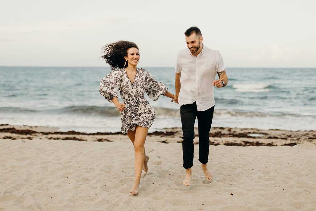 Couple holding hands and walking on the sand on the beach in front of the ocean
