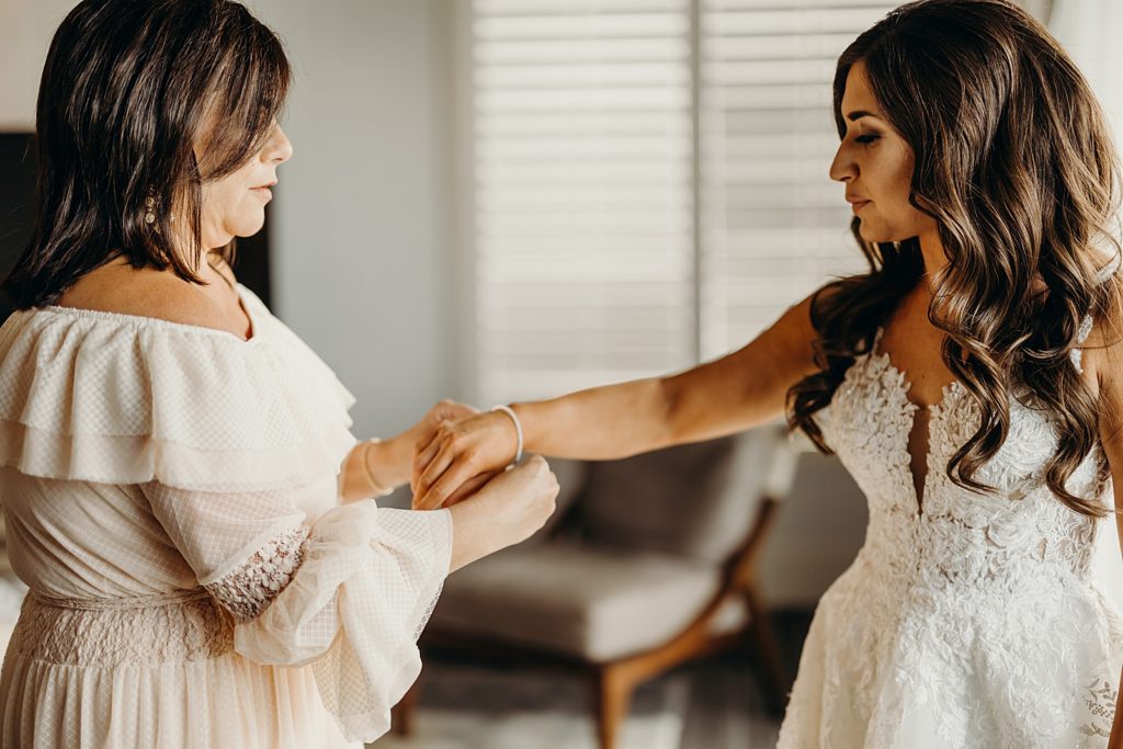 Mother helping Bride put bracelet on her getting ready