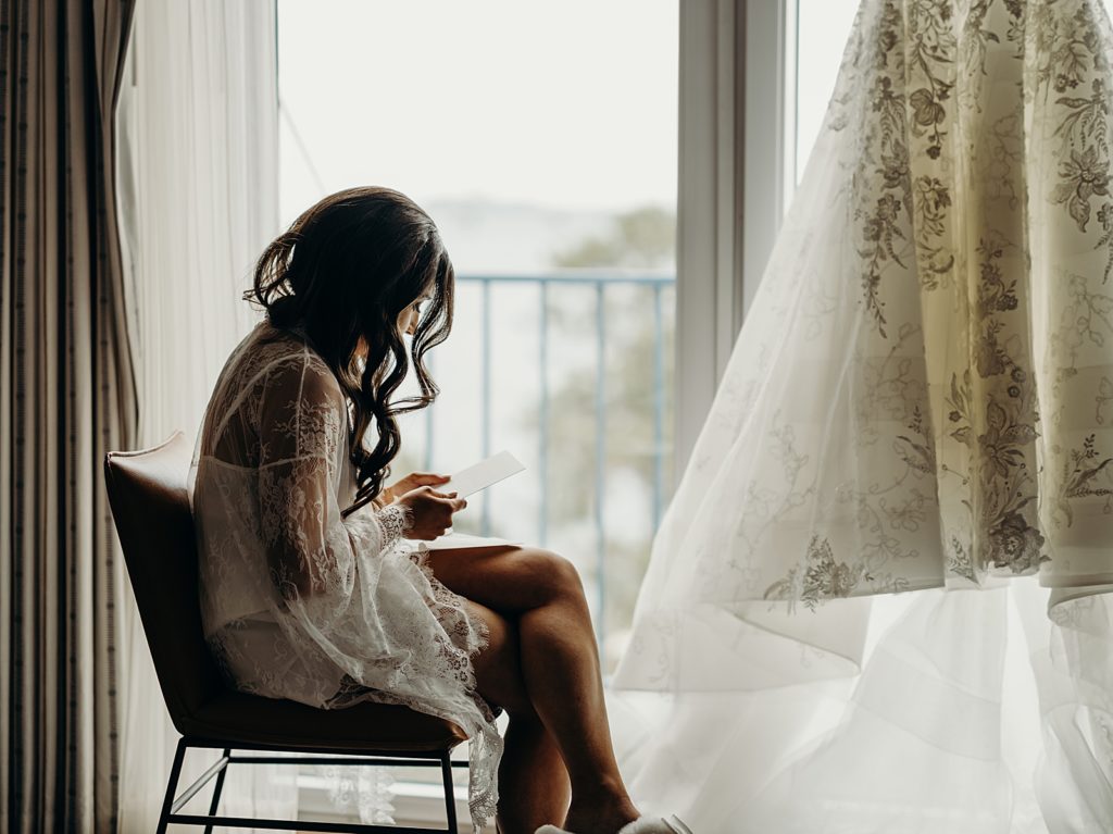 Bride sitting by window reading letter from Groom