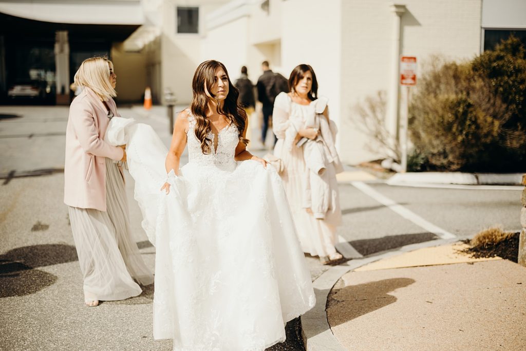 Bride walking outside with Bridesmaids helping with wedding train