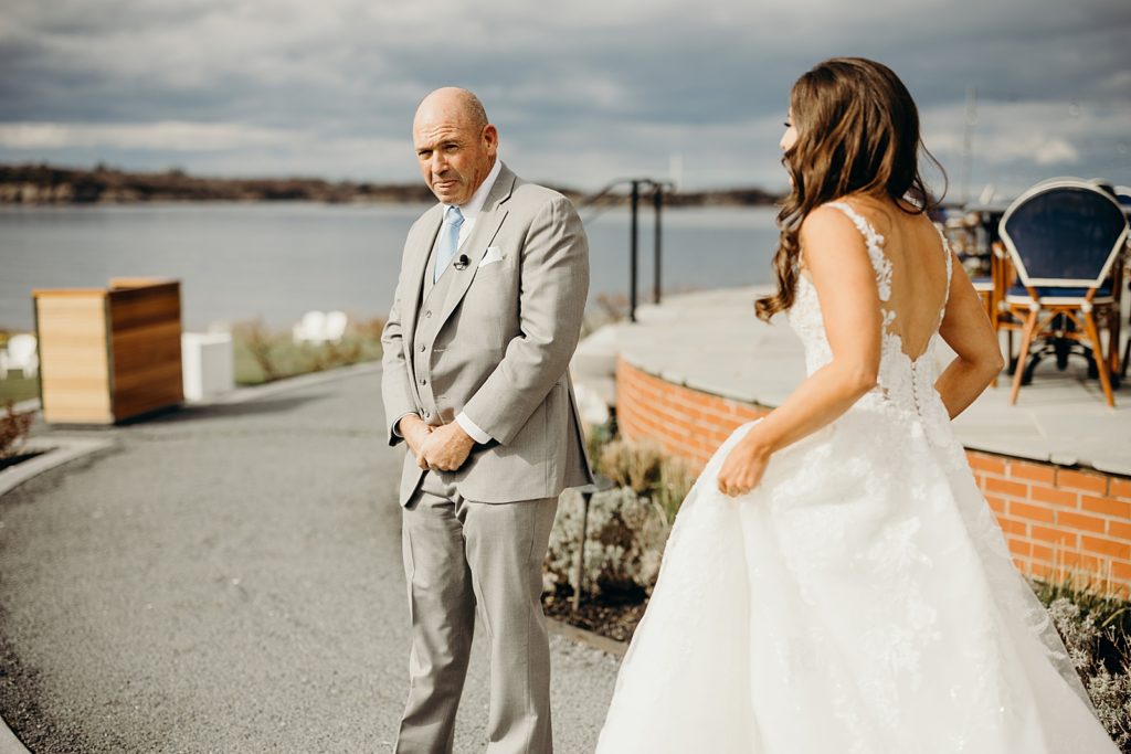 Father turning to see Bride in wedding dress by waterside