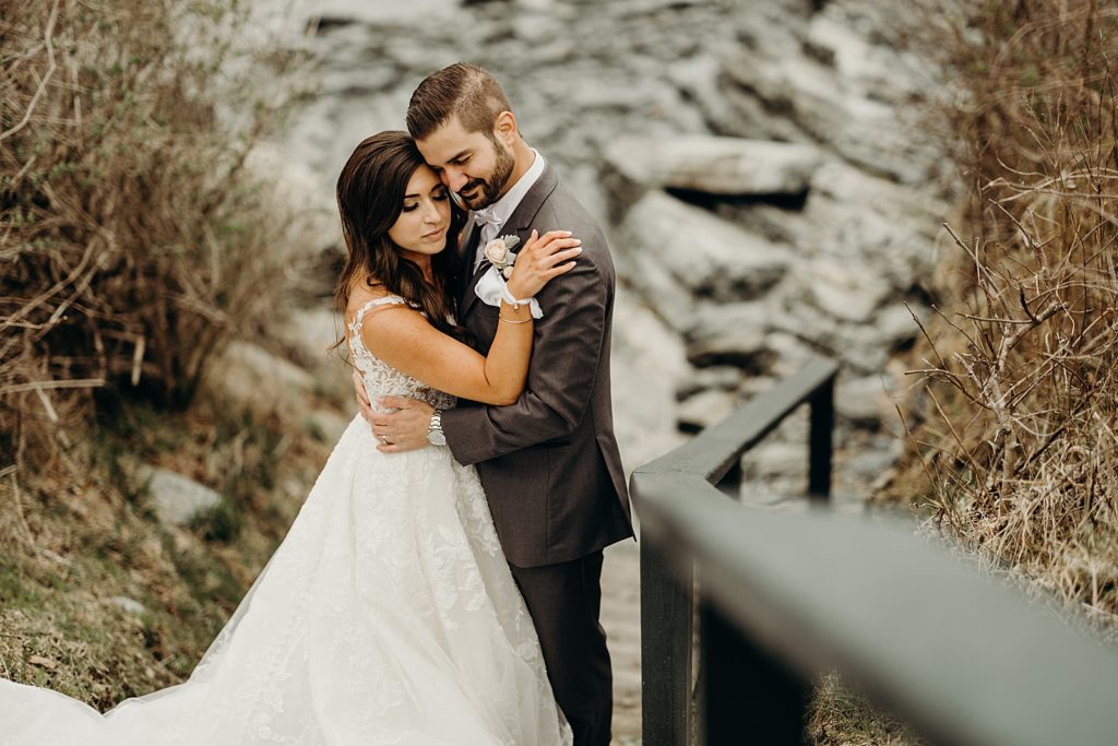 Bride and Groom hugging each other by the rocks and stairs on cliffside