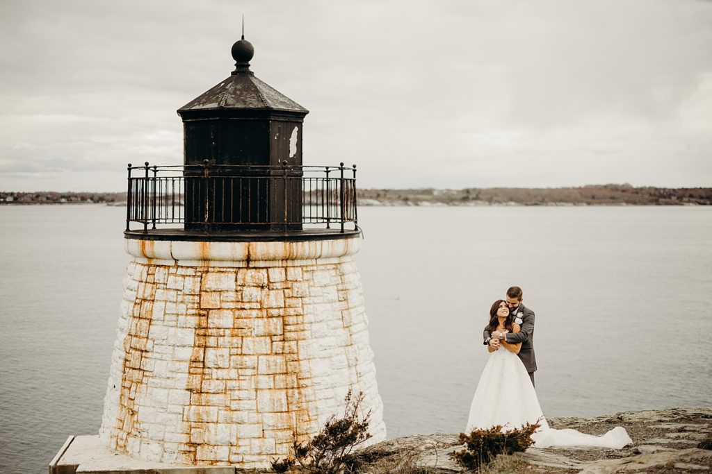 Groom holding Bride from behind by the the small lighthouse