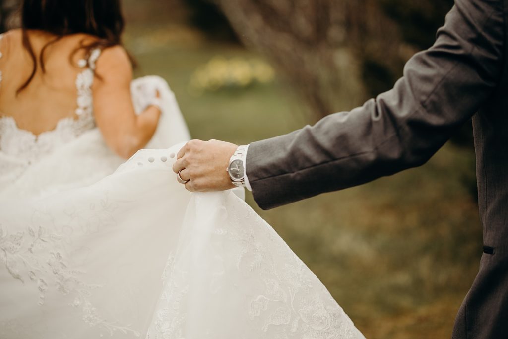 Closeup of Groom holding Bride's wedding dress