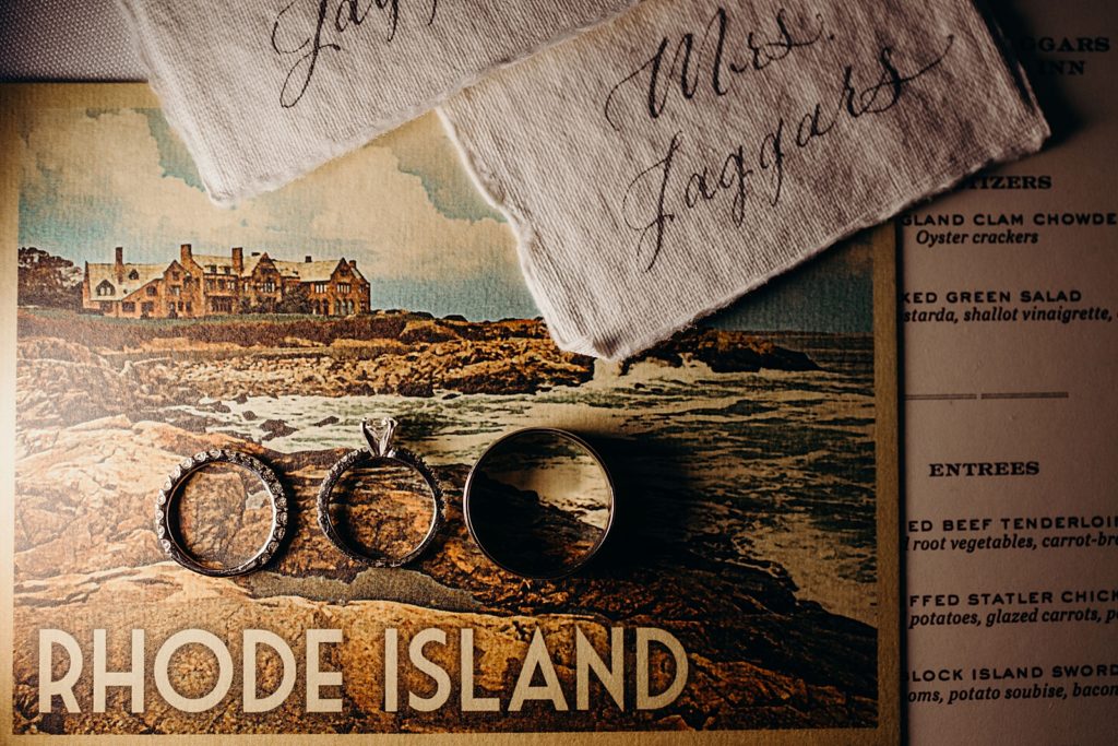 Detail shot of Rhode Island postcard with wedding bands and engagement ring on it