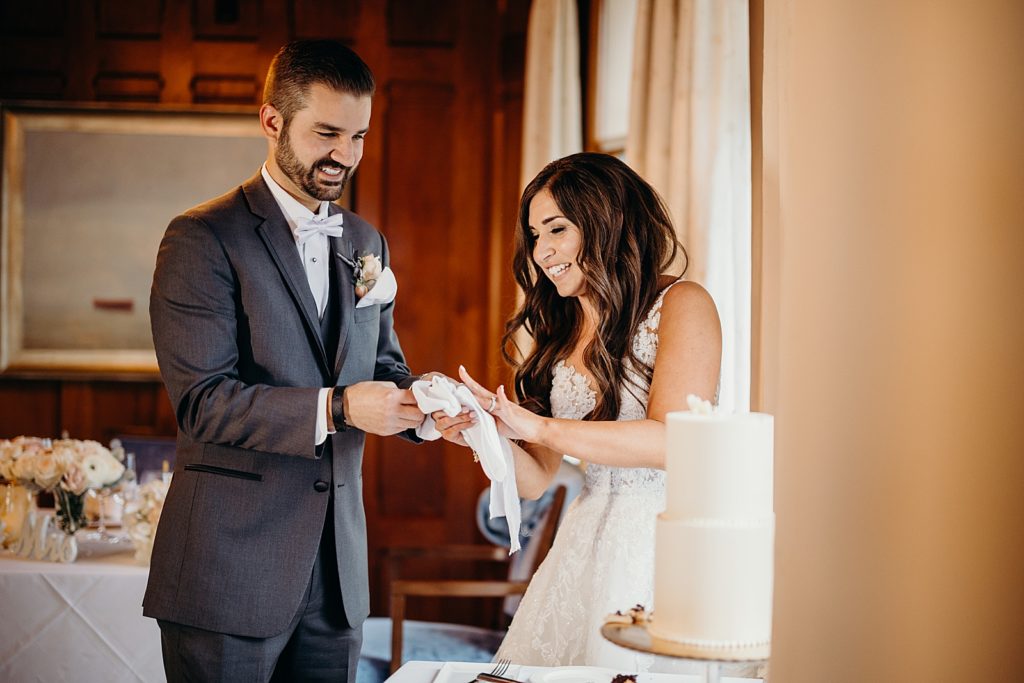 Bride and Groom wiping off cake knife and laughing for Reception