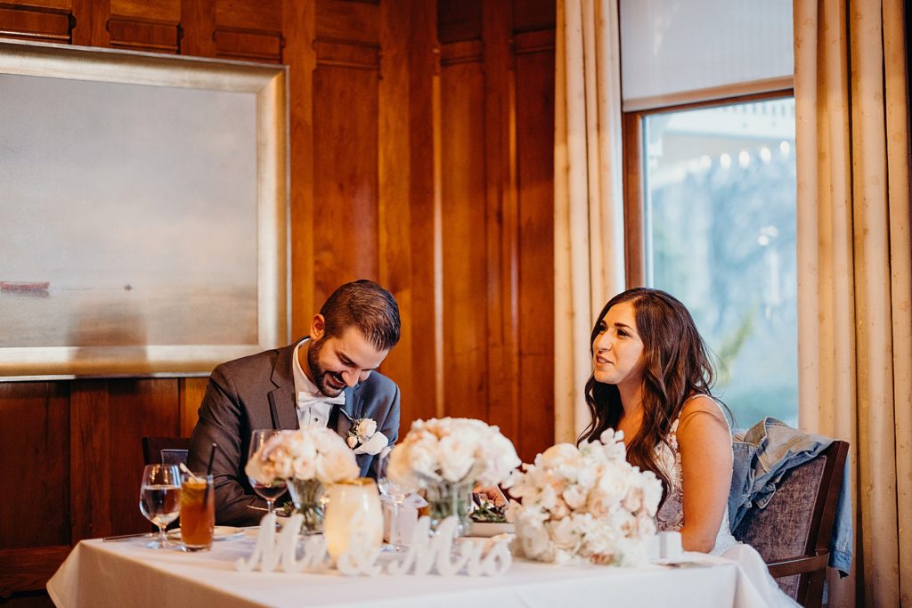Bride and Groom sitting at sweetheart table and laughing