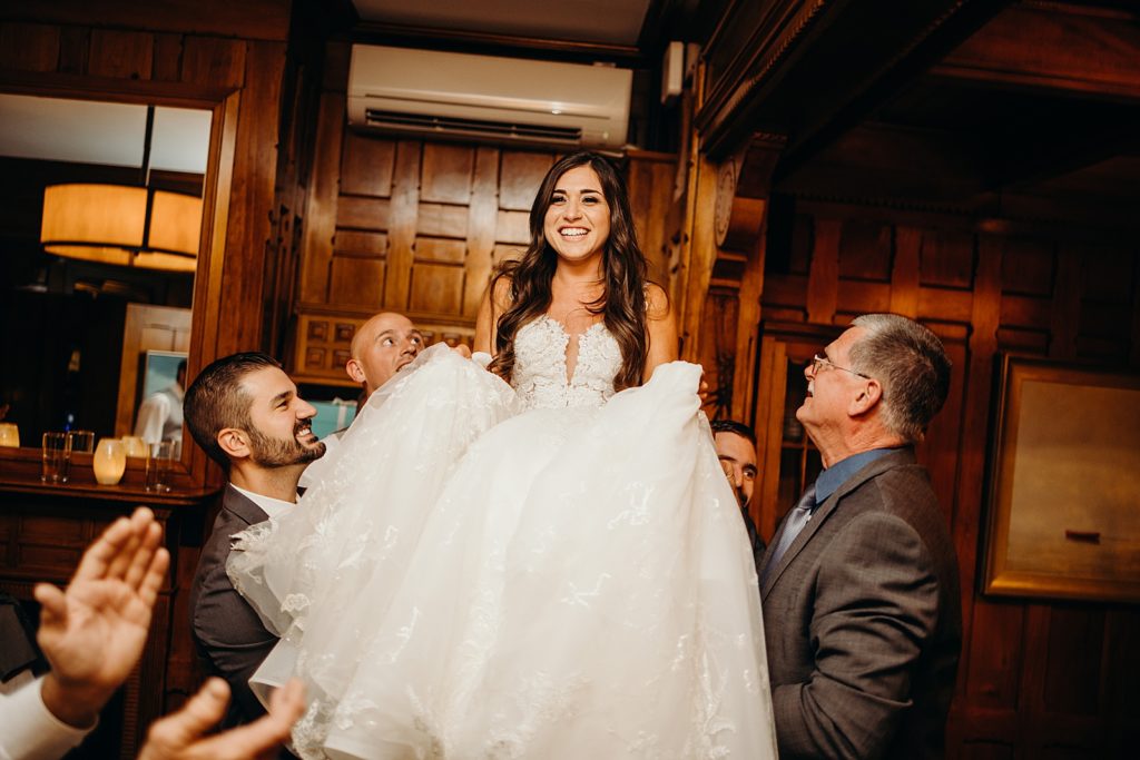 Bride being lifted up by Groom and family during Reception