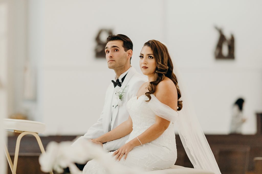 Bride and Groom sitting listening to Officiant during indoor Ceremony