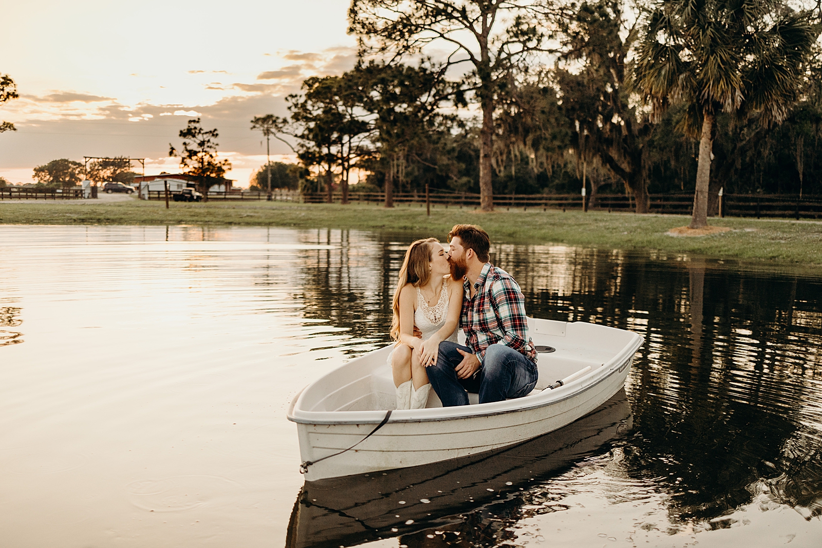 Couple sitting together and kissing on boat in the middle of the farm pond