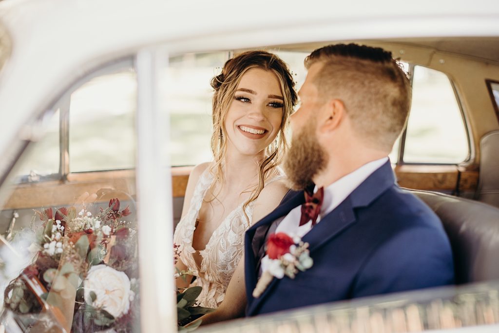 Bride and Groom in luxury classic car looking at each other