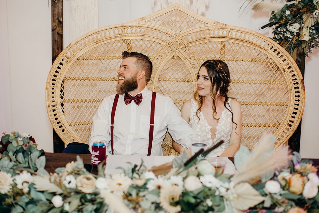 Bride and Groom listening to speech while sitting at sweetheart table