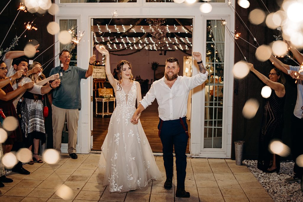 Bride and Groom holding hands as they exit Reception at night with sparklers