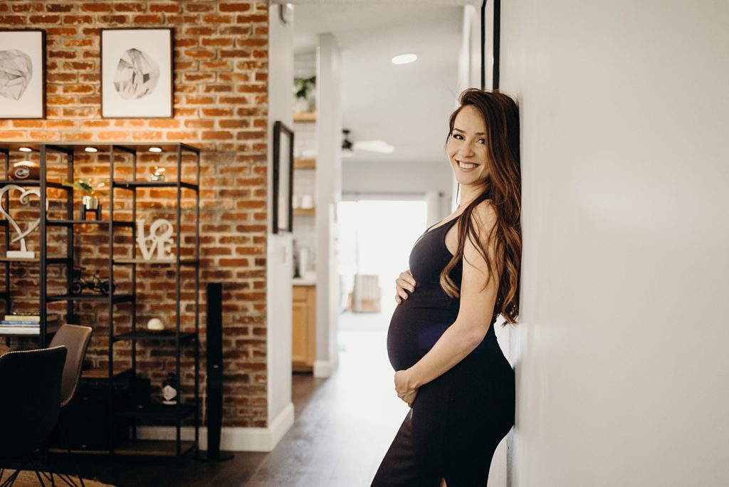 Portrait of woman leaning on wall while holding her baby bump