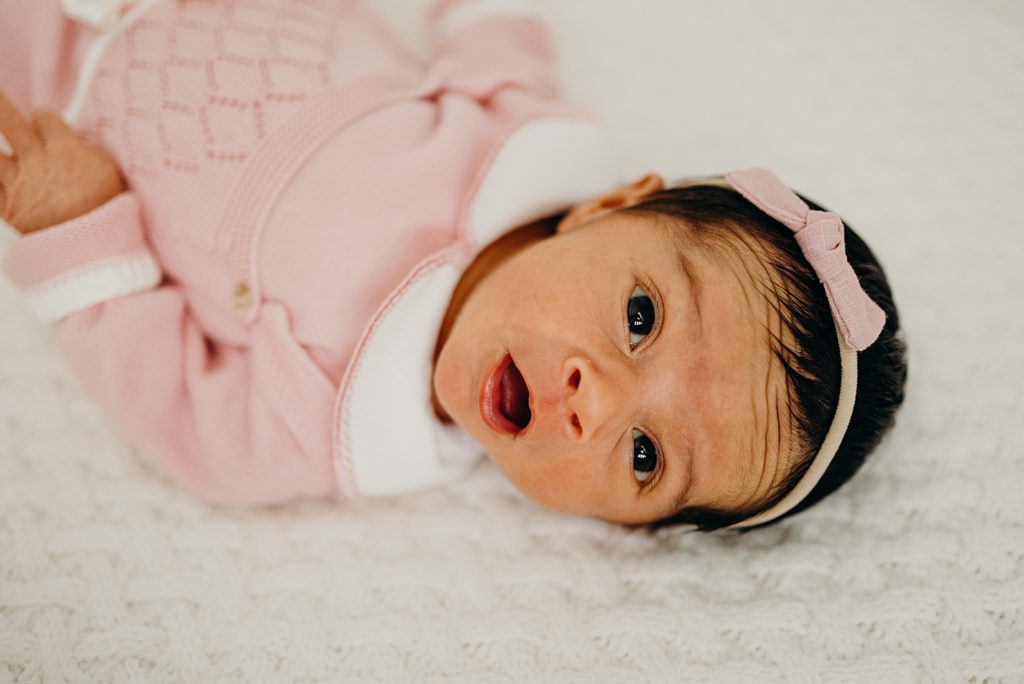 Closeup of baby in pink outfit with eyes open and mouth open