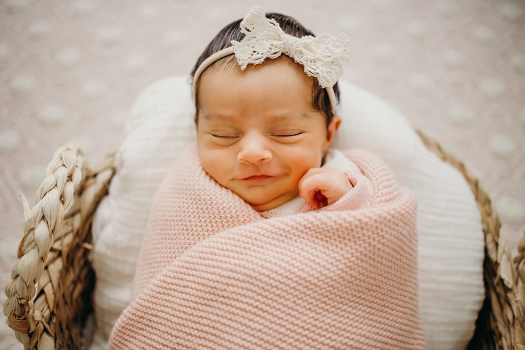 Toddler sleeping with eyes closed wrapped in swaddle in basket