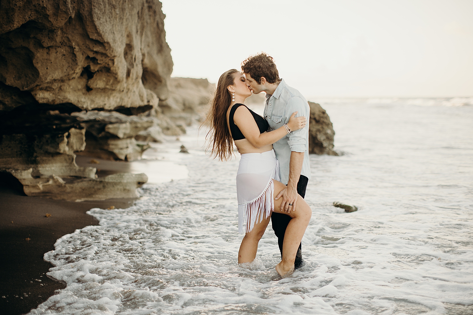 Couple kissing and holding each other as the ocean waves come in