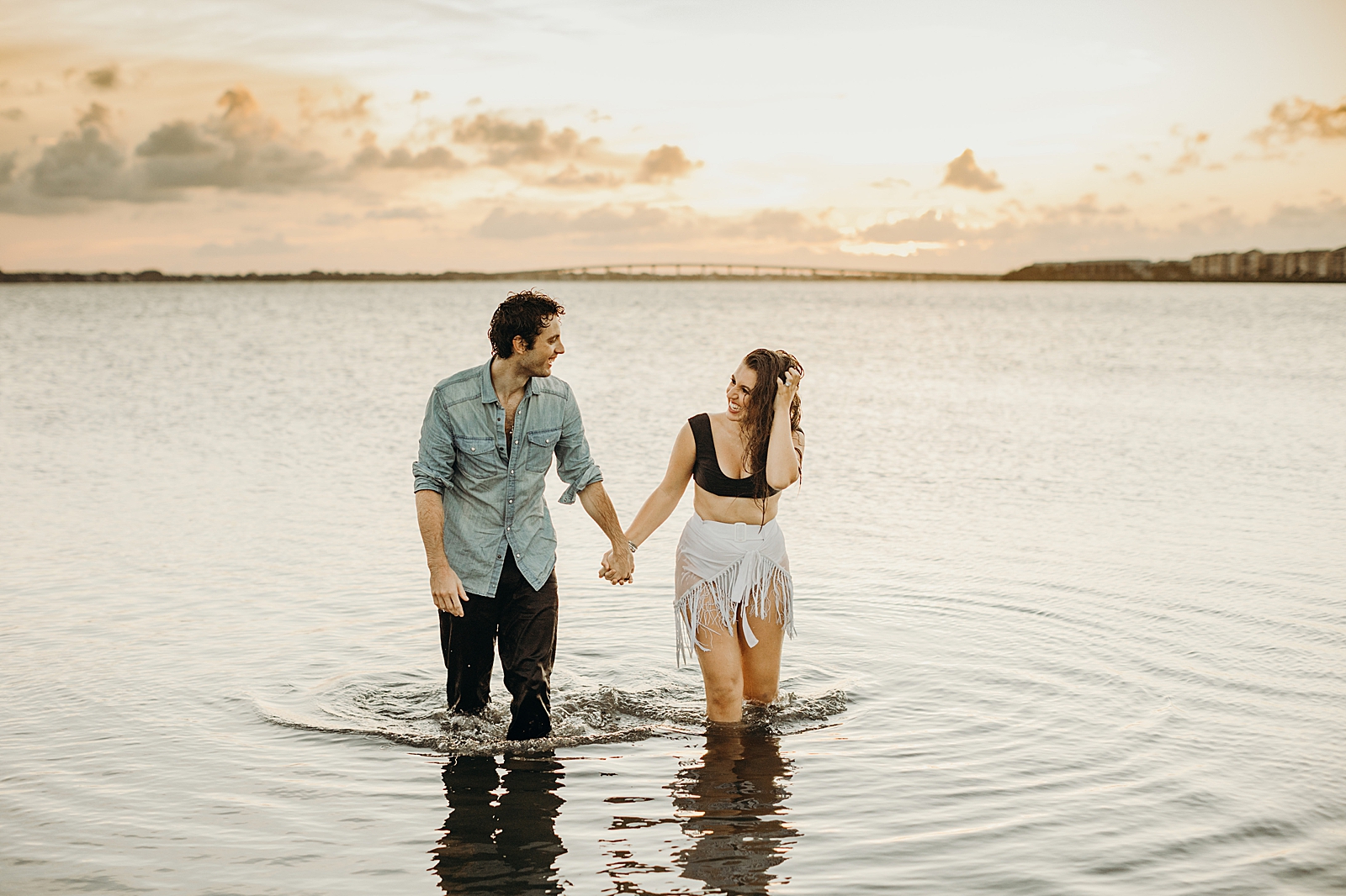 Couple walking in knee deep water looking at each other getting out of the ocean
