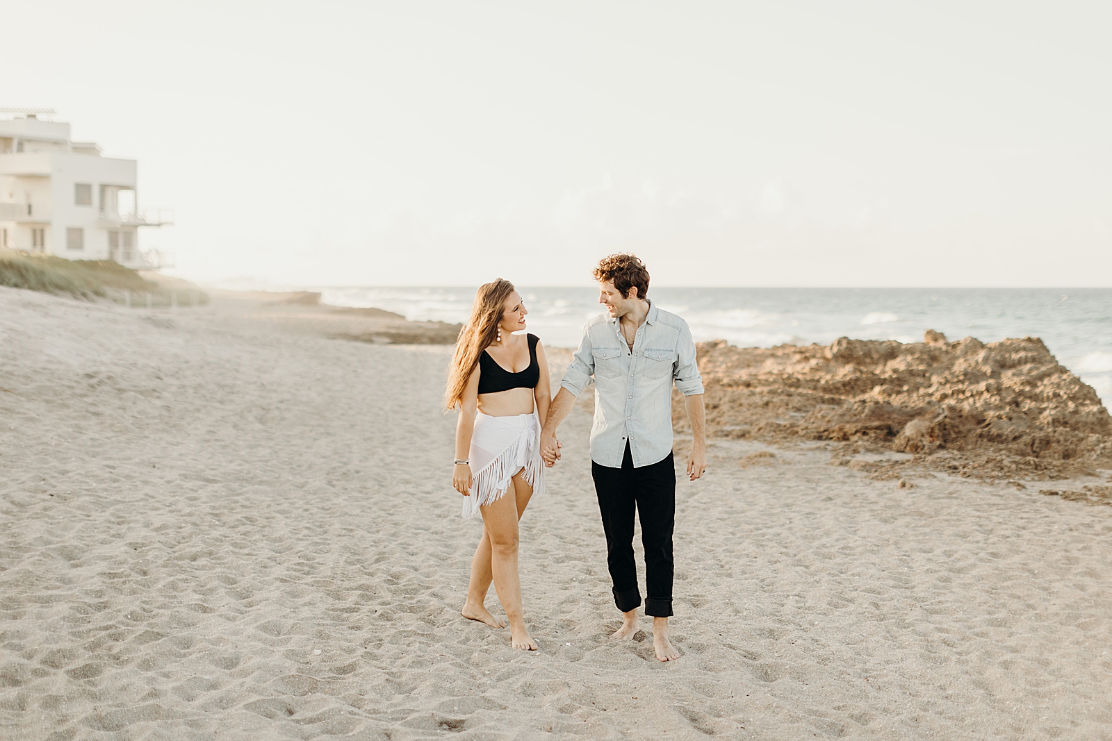 Couple holding hands walking barefoot on the sand of the beach