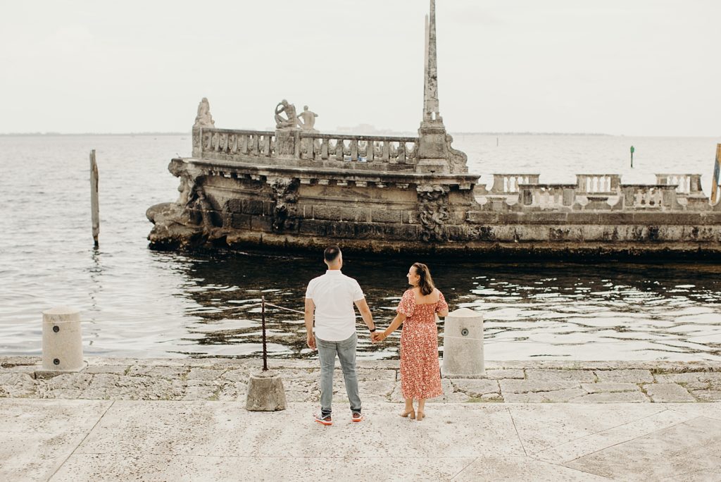 Couple holding hands and looking at ruin historic columns in the ocean