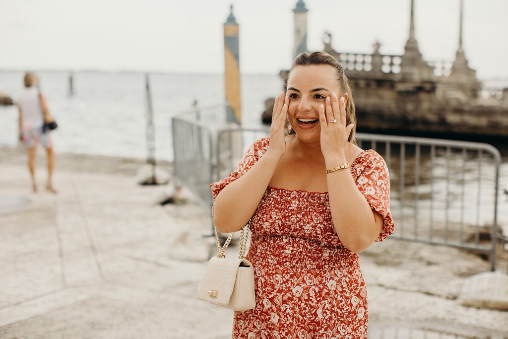Woman overjoyed after getting engagement with hands up by face with engagement ring on