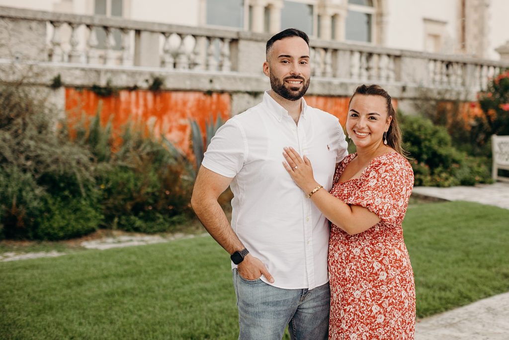 Just engaged couple in front of museum with woman's engagement ring hand on man's chest