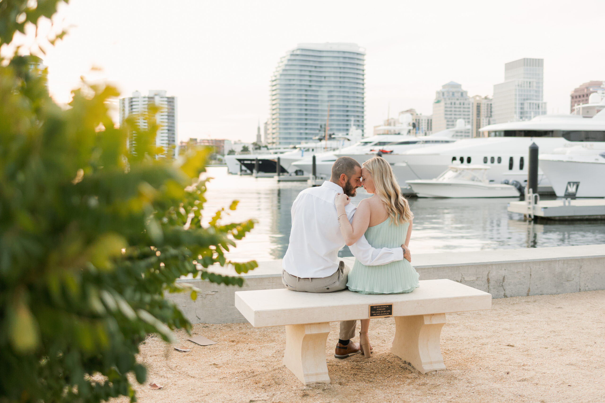 Couple sitting on a bench overlooking the Intracoastal and boats during a Palm Beach engagement session.