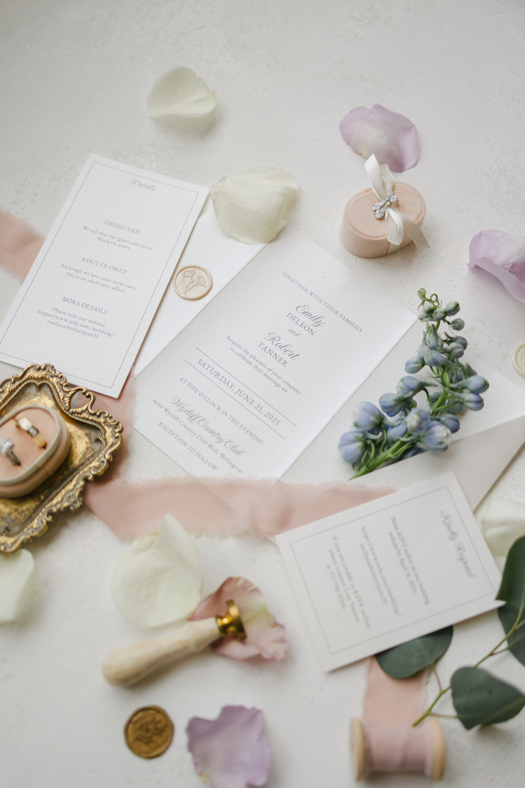 Overhead shot of wedding flat lay featuring invitation suite, wedding rings, floral accents, and heirloom jewelry arranged on a linen backdrop.
