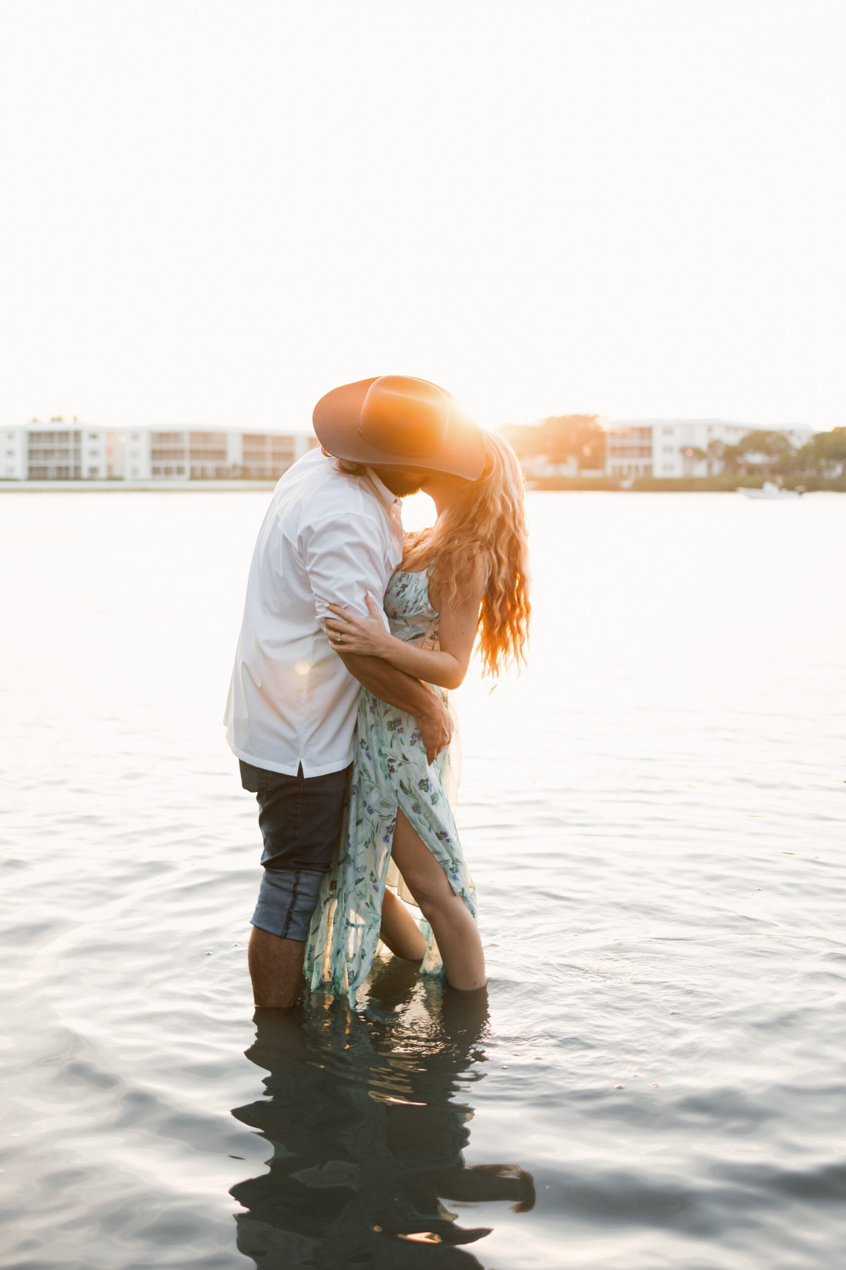 Couple kissing in the ocean at sunset during Palm Beach engagement photos at Coral Cove Park in Jupiter Florida.